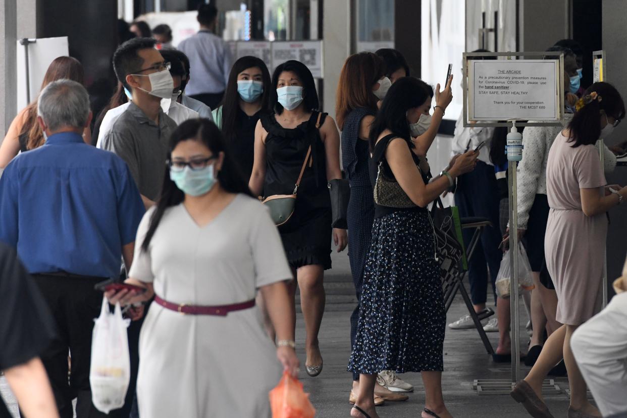 Office workers wearing face masks enter a building during lunch time in the financial business district in Singapore on August 11, 2020. - Singapore's virus-hammered economy shrank almost 43 percent in the second quarter, in a sign that the country's first recession in more than a decade was deeper than initially estimated, official data showed on August 11. (Photo by Roslan RAHMAN / AFP) (Photo by ROSLAN RAHMAN/AFP via Getty Images)