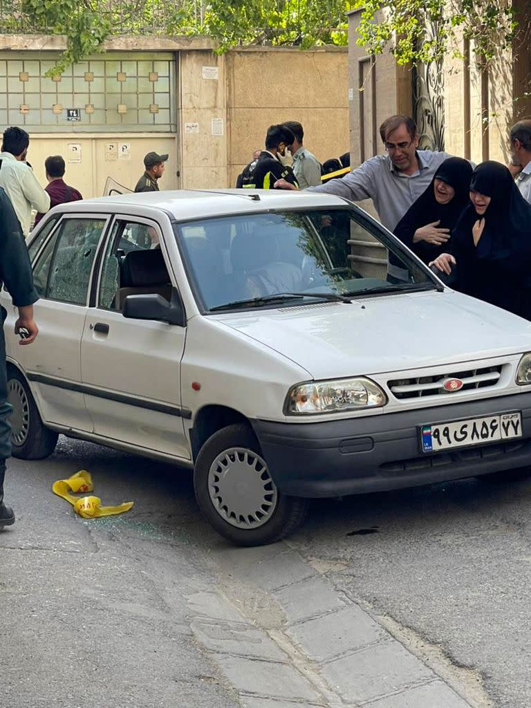 EDITORS NOTE: Graphic content / A picture shows two women mourning next to the body of Iranian Revolutionary Guards colonel Sayyad Khodai, after he was shot dead, in his car in the Iranian capital Tehran on May 22, 2022. - An Iranian Revolutionary Guards colonel was shot dead outside his Tehran home, the Guards said, blaming his "assassination" on assailants linked to the United States and its allies. The official news agency IRNA said Khodai was killed by five bullets as he returned home at around 4:00 pm (1130 GMT). (Photo by IRNA / AFP)