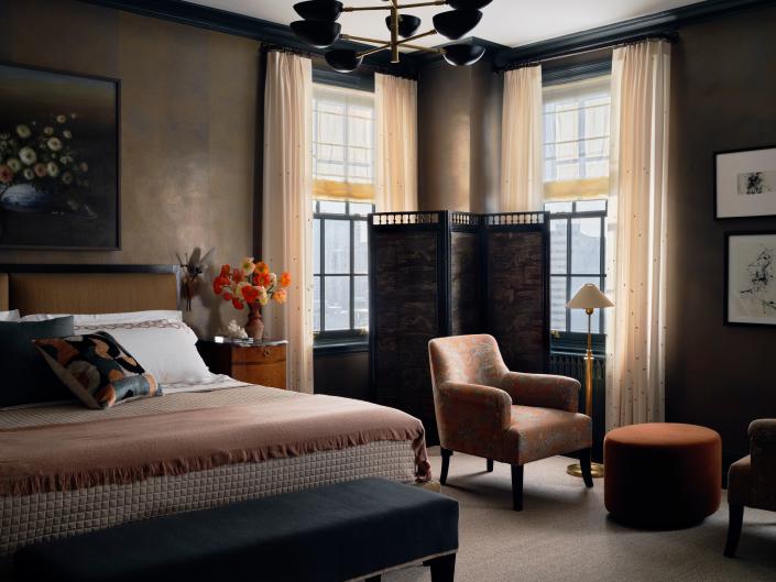 The black-lacquered light fixture and gold-toned floor lamp champion Deco sensibility in this bedroom designed by Jessica Lagrange Interiors.