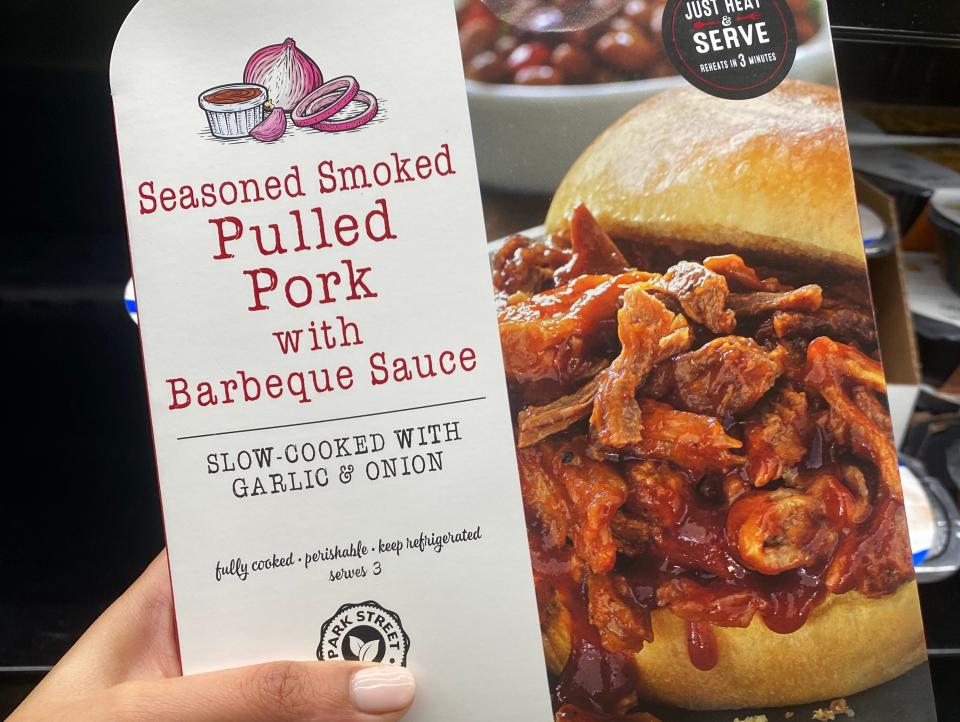 Hand holding pack of pulled pork at Aldi