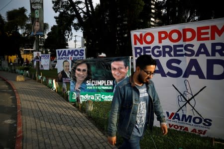 A man walks in front of a campaign signs, ahead of the second round run-off vote, in Guatemala City