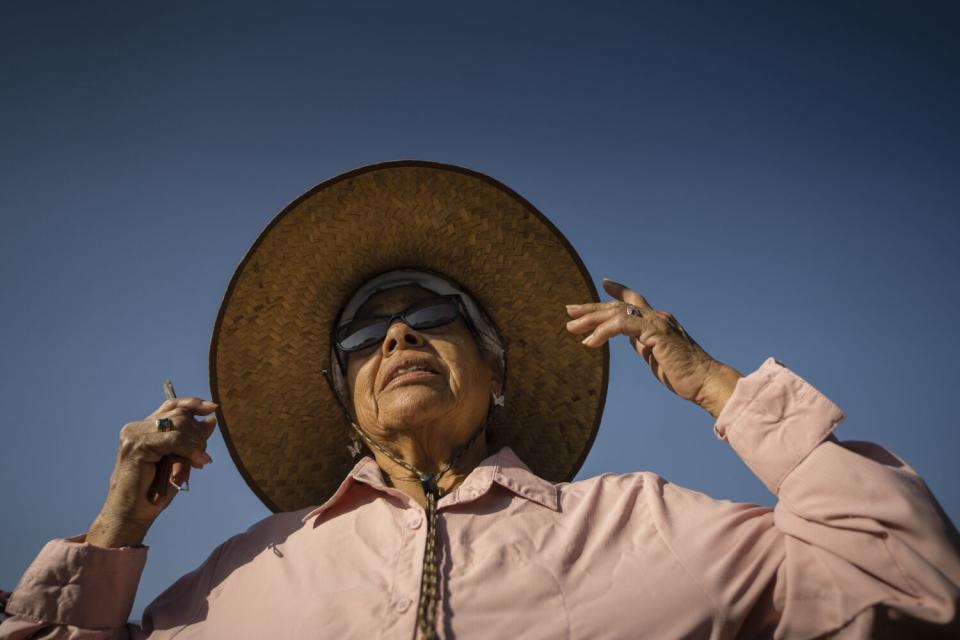 A woman wearing sunglasses and a big hat outdoors.