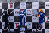 Team Penske driver Will Power, left, and Team Penske driver Scott McLaughlin, right, spray champaign on Chip Ganassi Racing driver Alex Palou, center, who won the race, following the Honda Indy Grand Prix of Alabama auto race at Barber Motorsports Parkway, Sunday, April 18, 2021, in Birmingham, Ala. (AP Photo/Vasha Hunt)