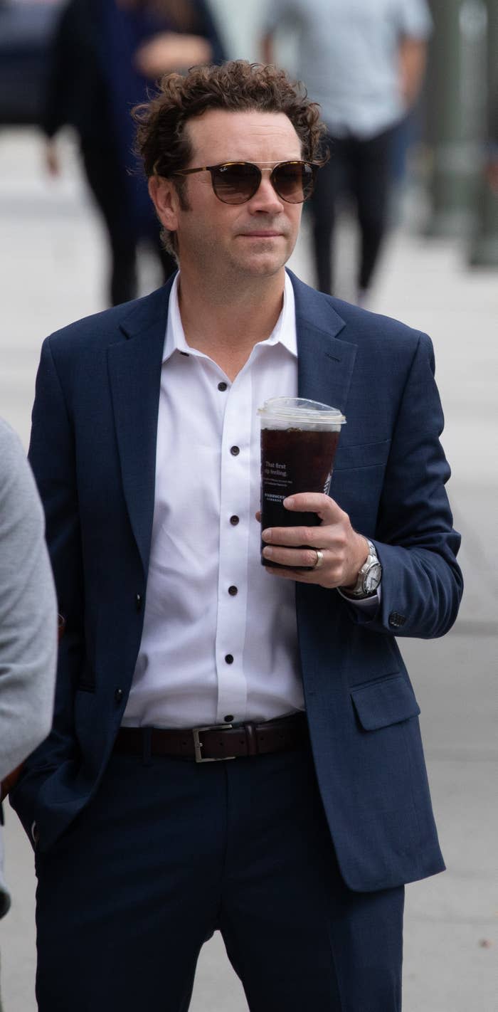 A closeup of danny walking outside with an iced coffee in hand