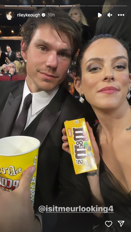 The couple is holding up m&ms and popcorn