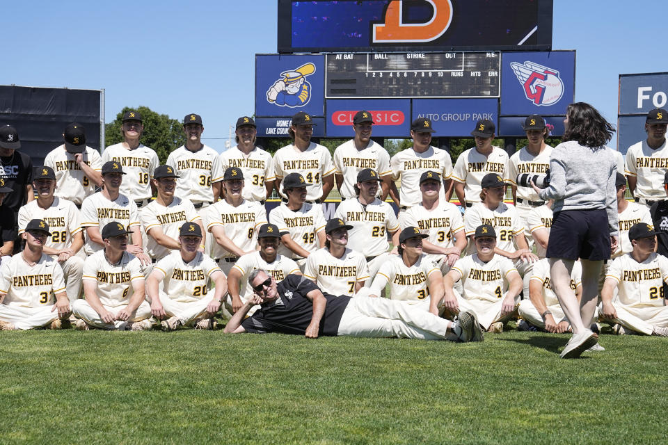 Birmingham-Southern head coach Jan Weisberg, front center, clowns around as photographer Amanda Phillips, right, directs players for a team photo, Thursday, May 30, 2024, in Eastlake, Ohio. On Friday, the Panthers will continue an unexpected, uplifting season that has captured hearts across the country by playing in the Division III World Series on the same day the liberal arts college founded on the eve of the Civil War shuts its doors. (AP Photo/Sue Ogrocki)