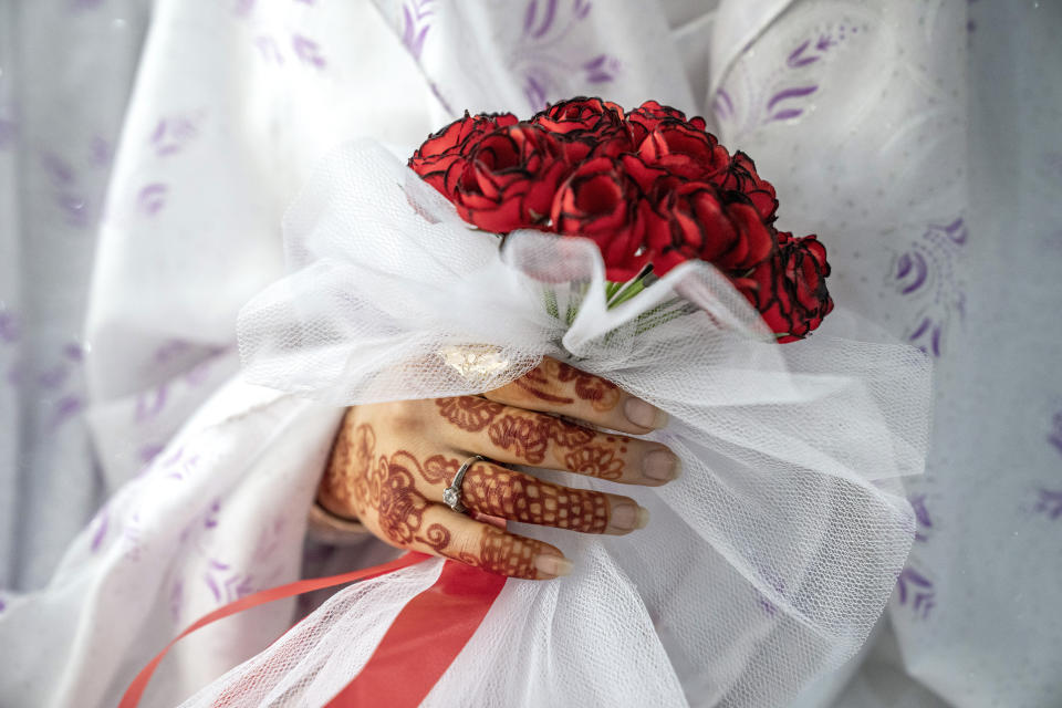 An Afghan bride holds a bouquet of roses at a mass wedding ceremony, during the International Women's Day in Kabul, Afghanistan, Wednesday, March 8, 2023. (AP Photo/Ebrahim Noroozi)