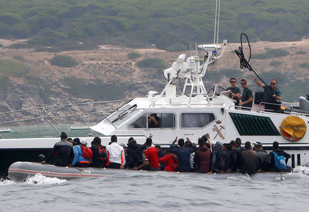 REFILE - REMOVING MIGRANTS' NATIONALITY A Spanish civil guard throws up a rope migrants as they try to stop them before disembarking from a dinghy at "Del Canuelo" beach after they crossed the Strait of Gibraltar sailing from the coast of Morocco, in Tarifa, southern Spain, July 27, 2018. REUTERS/Stringer