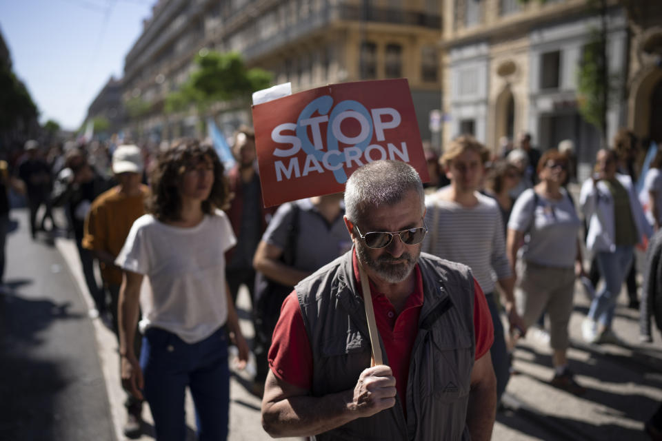 A protester holds a sign reading "Stop Macron" during a May Day demonstration in Marseille, southern France, Sunday, May 1, 2022. May 1 is celebrated as the International Labour Day or May Day across the world. (AP Photo/Daniel Cole)