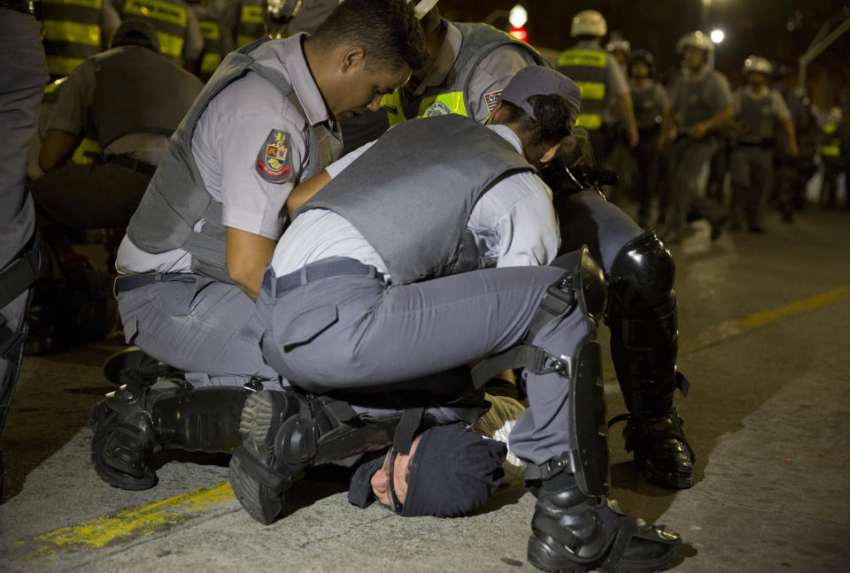 Policemen detain a demonstrator during a protest against the upcoming World Cup soccer tournament in Sao Paulo, Brazil, Saturday, Feb. 22, 2014. Hundreds of protesters gathered demonstrating against the billions of dollars being spent to host this year's World Cup while the nation's public services remain in a woeful state. The protest started peacefully, but adherents to the Black Block anarchist tactics vandalized banks and clashed with police, who used tear gas and stun grenades to disperse the violent demonstrators. (AP Photo/Andre Penner)