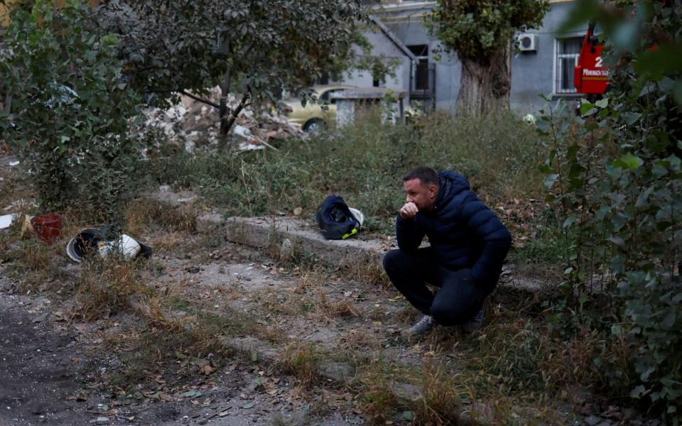 A local resident sits at a site of a residential building heavily damaged by a Russian missile strike - Reuters