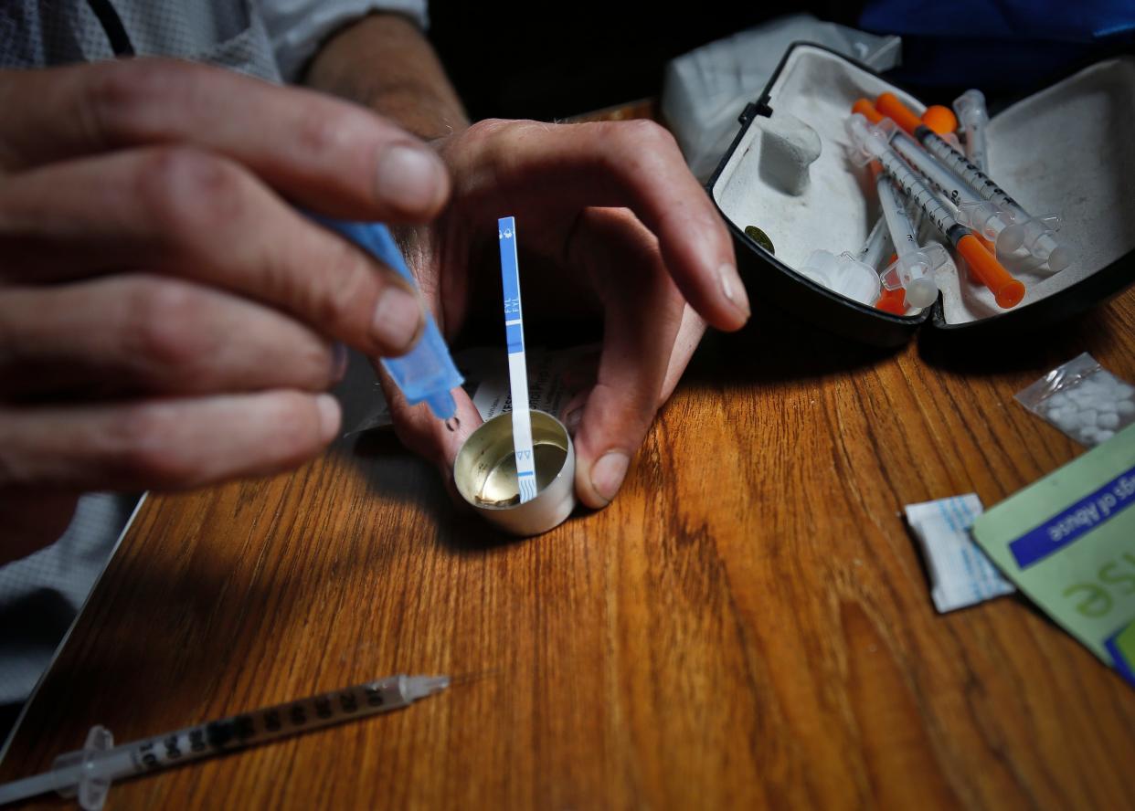 A drug user prepares heroin, placing a fentanyl test strip into the mixing container to check for contamination.