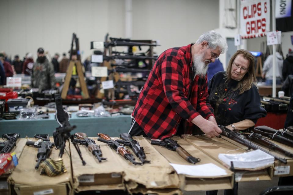 Mike Sadley, 64, and his wife, Jennie Sadley, 59, both of Wayne look over different guns, during the Novi Gun and Knife Show at Suburban Collection Showplace in Novi, Mich. on Feb. 24, 2018.