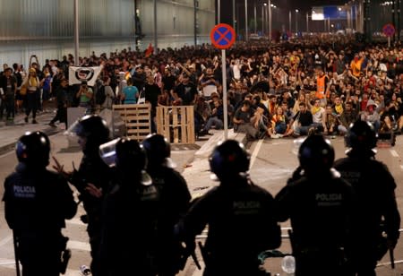 Police officers face protesters during a demonstration at the airport, after a verdict in a trial over a banned independence referendum, in Barcelona