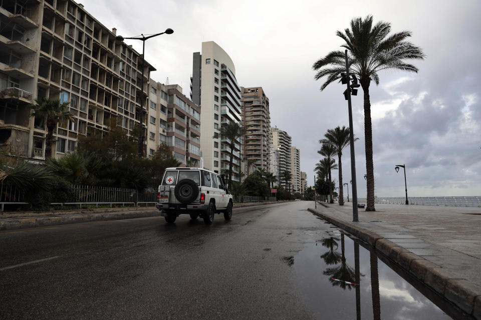 A Red Cross vehicle drives along the empty waterfront promenade as the country starts a new lockdown, in Beirut, Lebanon, Thursday, Jan. 14, 2021. Lebanese authorities began enforcing an 11-day nationwide shutdown and round the clock curfew Thursday, hoping to limit the spread of coronavirus infections spinning out of control after the holiday period. (AP Photo/Bilal Hussein)