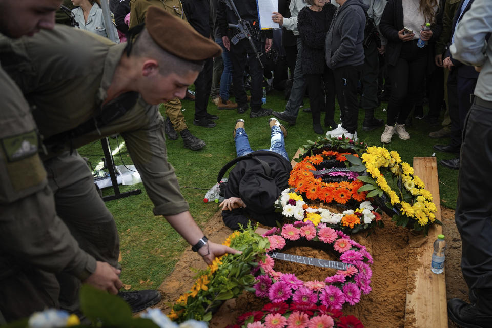 Family and friends of Israeli soldier Major Roei Meldasi mourn over his grave during his funeral in Afula, Israel, Wednesday, Dec. 13, 2023. Meldasi, 23, was killed during a military ground operation in the Gaza Strip. (AP Photo/Ariel Schalit)