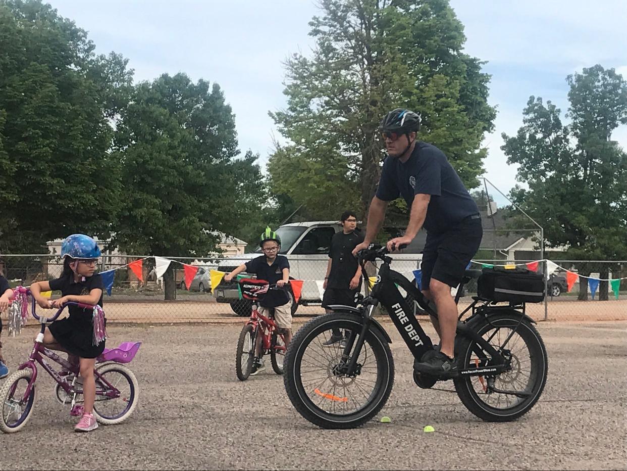 Pueblo Fire Captain Ryan Moran demonstrates safe techniques for riding a bike at St. John Neumann Catholic School On May 19, 2022.