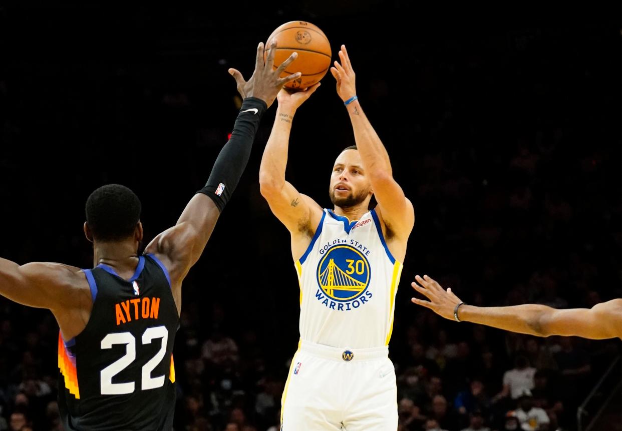 Nov 30, 2021; Phoenix, Arizona, USA; Phoenix Suns center Deandre Ayton (22) pressures a shot by Golden State Warriors guard Stephen Curry (30) at Footprint Center.