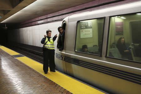 A Bay Area Rapid Transit (BART) police officer gestures to a BART conductor after demonstrators forced officials to shut down the tracks in San Francisco, California January 16, 2015. REUTERS/Robert Galbraith