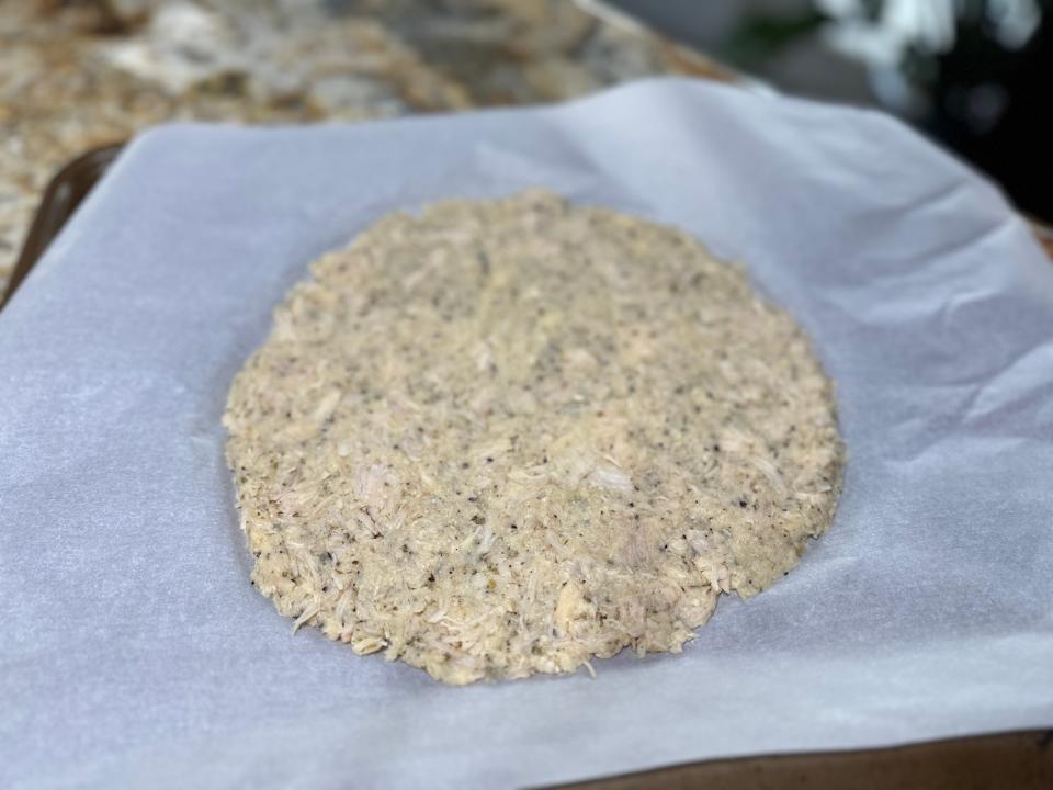 Chicken crust pressed into round shape on parchment paper 