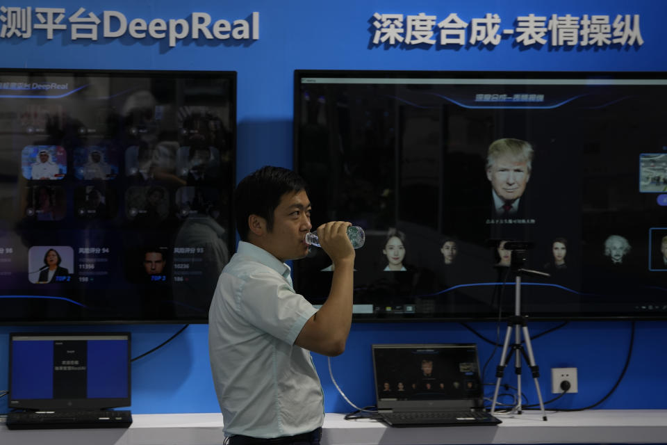 A vendor walks past screens depicting facial deep fake technologies depicting former U.S. President Donald Trump at the Security China 2023 expo in Beijing, on June 7, 2023. After years of breakneck growth, China's security and surveillance industry is now focused on shoring up its vulnerabilities to the United States and other outside actors, worried about risks posed by hackers, advances in artificial intelligence and pressure from rival governments. The renewed emphasis on self-reliance, combating fraud and hardening systems against hacking was on display at the recent Security China exhibition in Beijing. (AP Photo/Ng Han Guan)