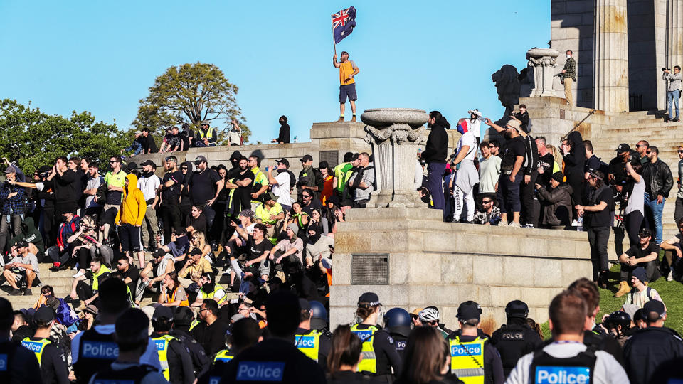 A man, pictured here waving the Australian flag on the steps of the Shrine of Remembrance. 