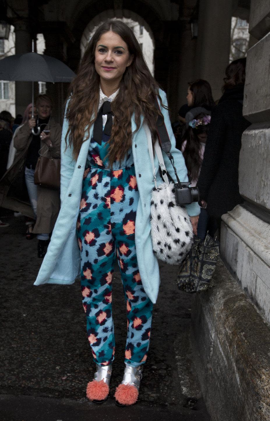 A woman wearing a colorful outfit shelters from the rain on the first day of London Fashion Week, in London, Friday, Feb. 14, 2014. (AP Photo/Alastair Grant)