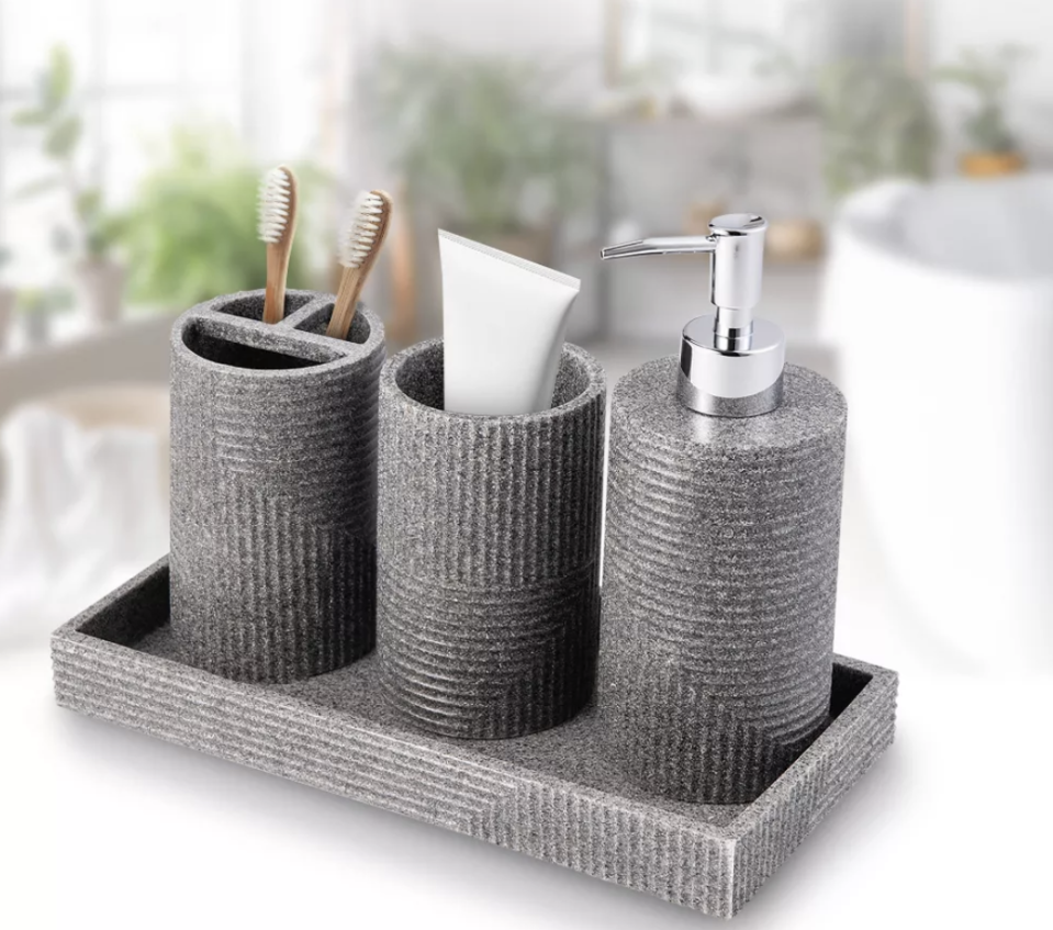 the gray four-piece bathroom accessory set with a tray, toothbrush holder, pump dispenser, and cotton ball holder
