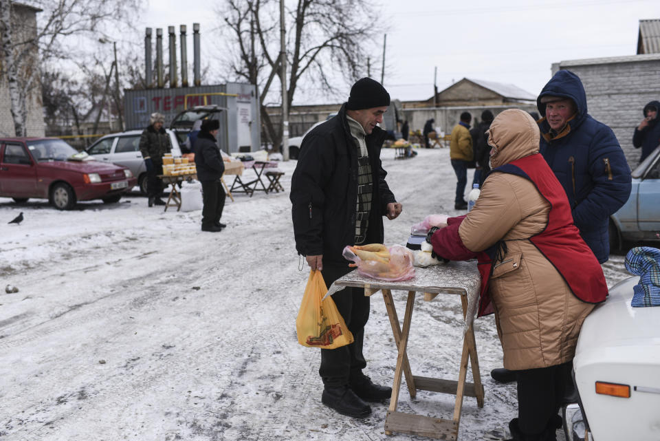In this photo taken on Saturday, Dec. 1, 2018, people buy and sell at Saturday's market in Milove, eastern Ukraine, one village, that is split in two by a barbed wire border between Ukraine and Russia. People on the streets easily mix both Russia and Ukrainian languages without making a political statement of it, but earlier this year, Russia built a barbed wire fence on the Friendship of People's street, marking the border with Ukraine in a metaphorical statement about the long-simmering conflict between the countries.(AP Photo/Evgeniy Maloletka)