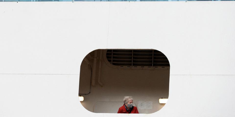 A woman looks out from the Coral Princess cruise ship docked at the International Terminal on Circular Quay in Sydney on July 13, 2022