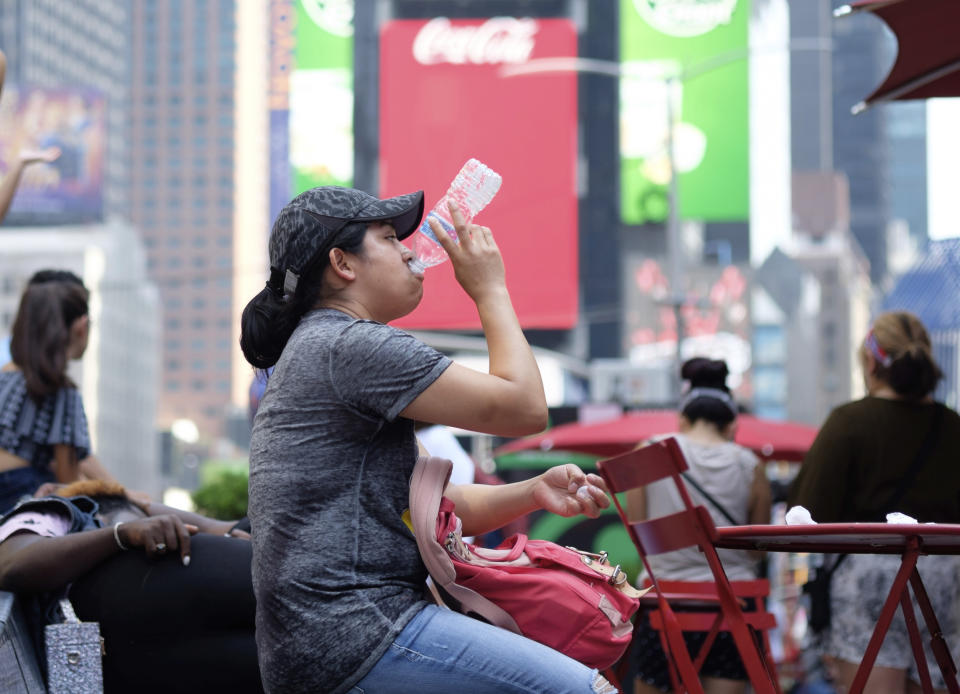 A woman drinks water in Times Square as temperatures reach the mid-to-upper 90s Saturday, July 20, 2019, in New York. Americans from Texas to Maine sweated out a steamy Saturday as a heat wave spurred cancelations of events from festivals to horse races and the nation’s biggest city ordered steps to save power to stave off potential problems. (AP Photo/Jonathan Carroll)