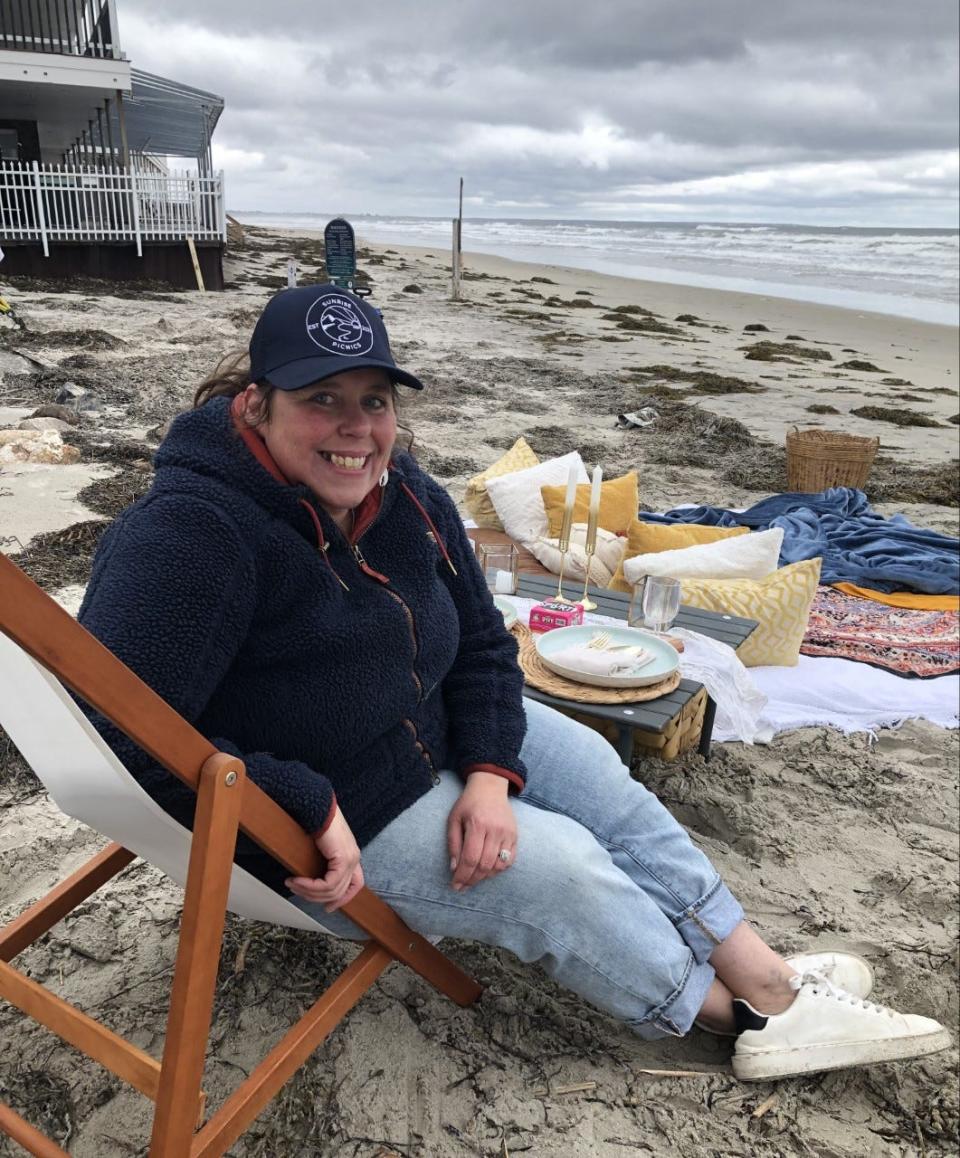 Megan Petrus, the owner of Sunrise Picnics, sits near a picnic site she set up on Ogunquit Beach in Ogunquit, Maine, on May 4, 2023.