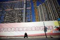 Man sits in front of a construction site in Beijing