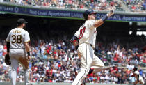 Atlanta Braves' Austin Riley, right, celebrates after hitting his second home run while rounding first base past Pittsburgh Pirates' Will Craig during the third inning of a baseball game Sunday, May 23, 2021, in Atlanta. (Curtis Compton/Atlanta Journal-Constitution via AP)