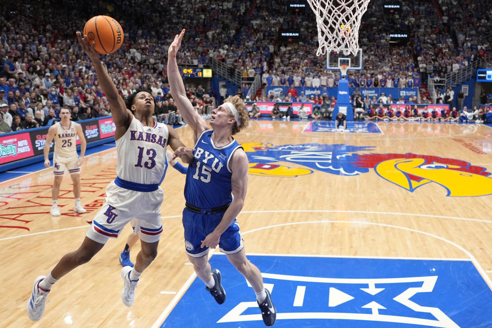 Kansas guard Elmarko Jackson (13) shoots over BYU guard Richie Saunders (15) during the first half of an NCAA college basketball game Tuesday, Feb. 27, 2024, in Lawrence, Kan. (AP Photo/Charlie Riedel)