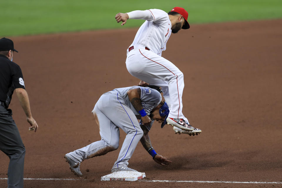 Cincinnati Reds' Eugenio Suarez (7) leaps over and applies the tag as Kansas City Royals' Adalberto Mondesi (27) steals third base safely on a wild pitch in the fourth inning during a baseball game at in Cincinnati, Wednesday, Aug. 12, 2020. (AP Photo/Aaron Doster)