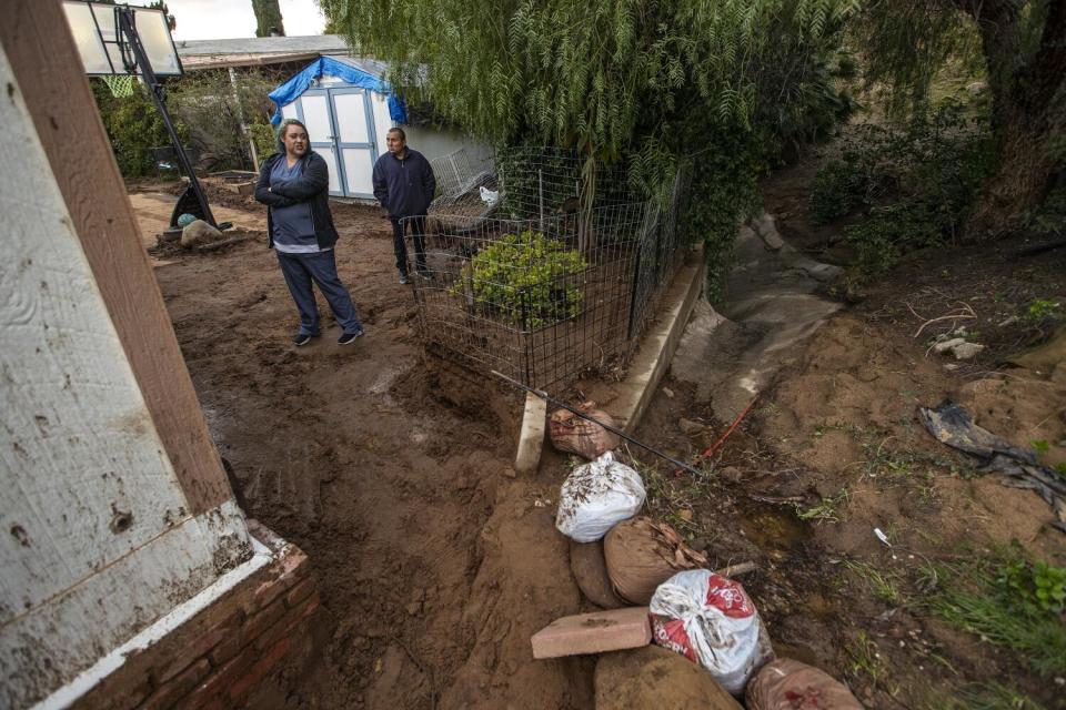 A family is photographed next to their home that was damaged as a result of a landslide from all the recent rain.