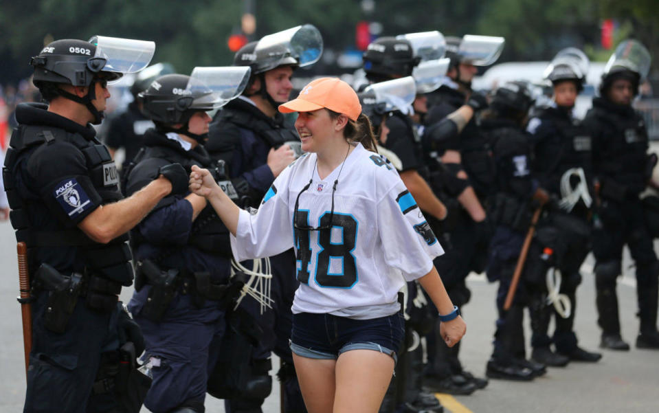 <p>A football fan greets police in riot gear as she leaves the football game between the Carolina Panthers and the Minnesota Vikings in Charlotte, N.C., on Sept. 25, 2016. (Mike Blake/Reuters)</p>