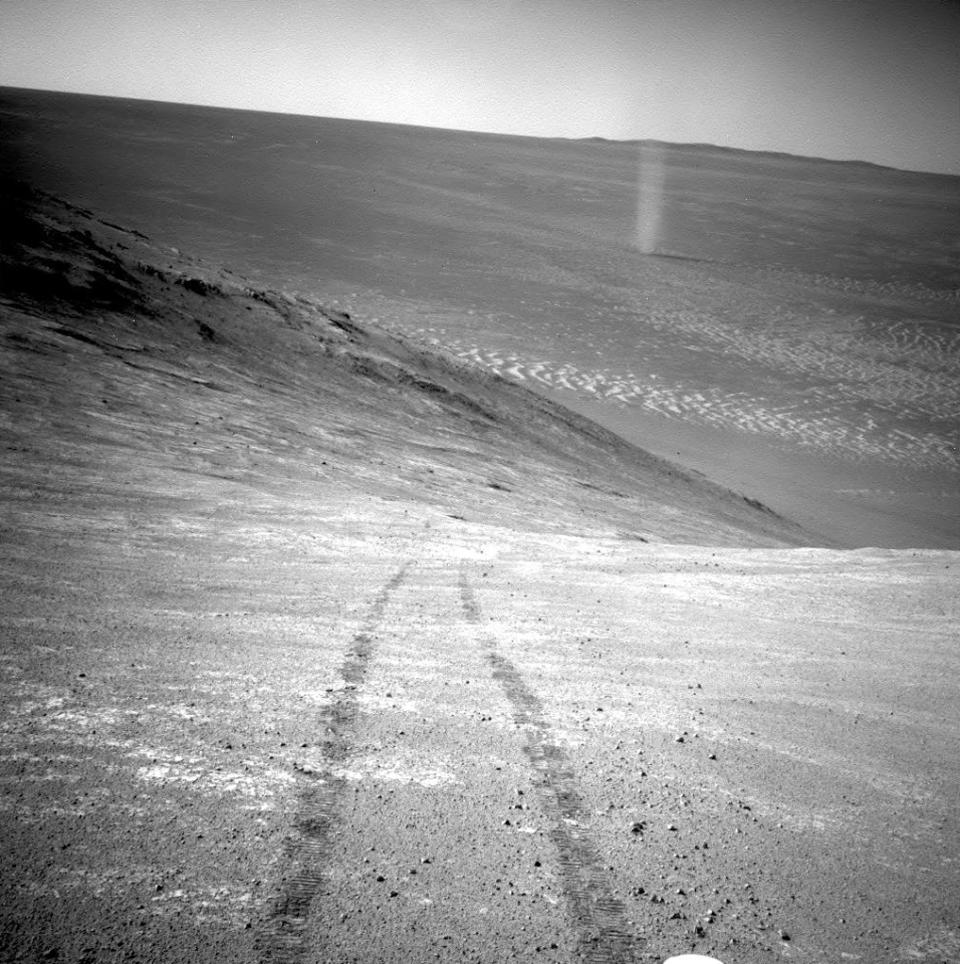 This March 31, 2016 photo made available by NASA shows a dust devil in a valley on Mars, seen by the Opportunity rover perched on a ridge. The view looks back at the rover's tracks leading up the north-facing slope of "Knudsen Ridge," which forms part of the southern edge of "Marathon Valley." (NASA/JPL-Caltech via AP)