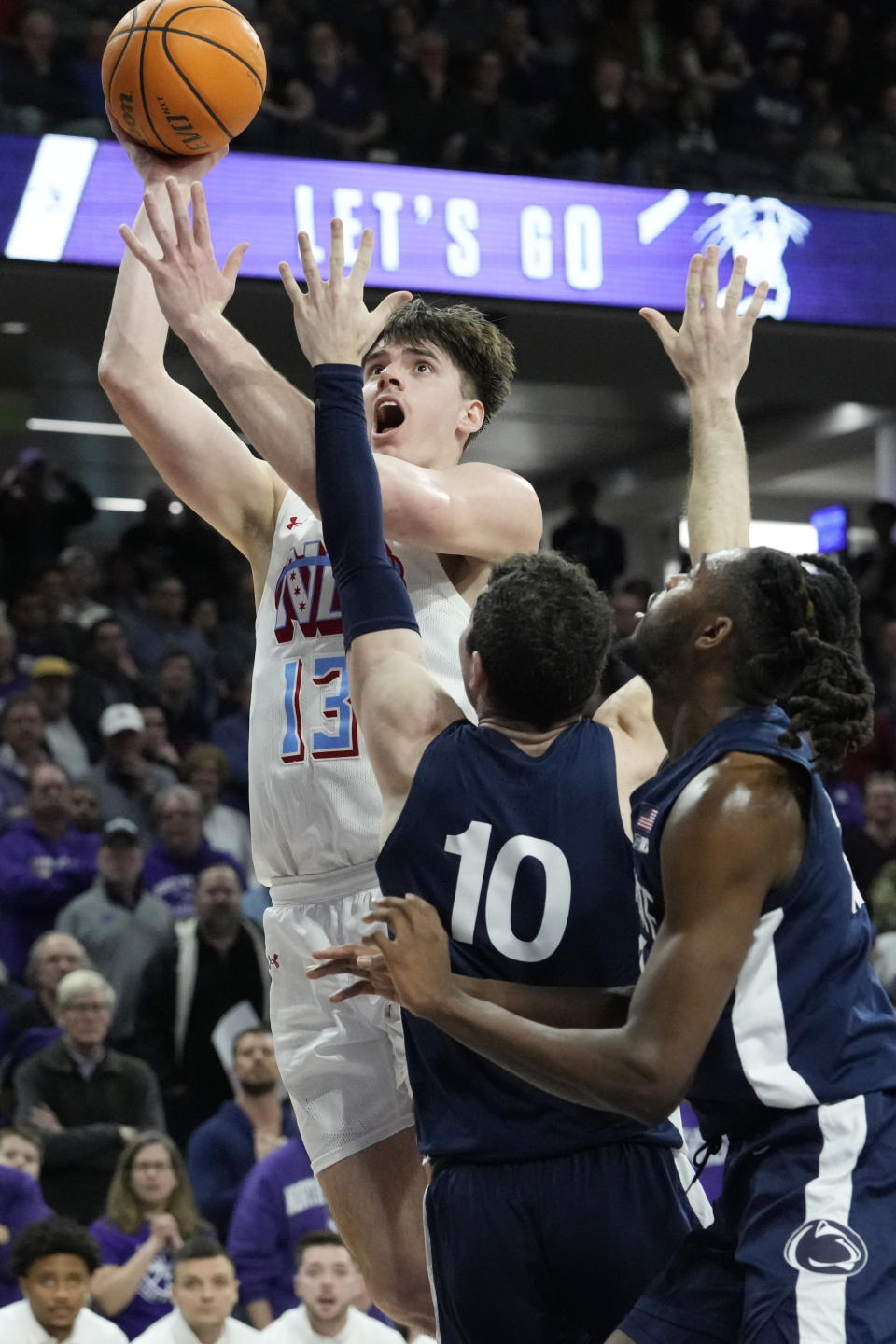Northwestern guard Brooks Barnhizer (13) drives to the basket against Penn State guard Andrew Funk (10), and guard Evan Mahaffey (12) during overtime of an NCAA college basketball game in Evanston, Ill., Wednesday, March 1, 2023. Penn State won 68-65. (AP Photo/Nam Y. Huh)
