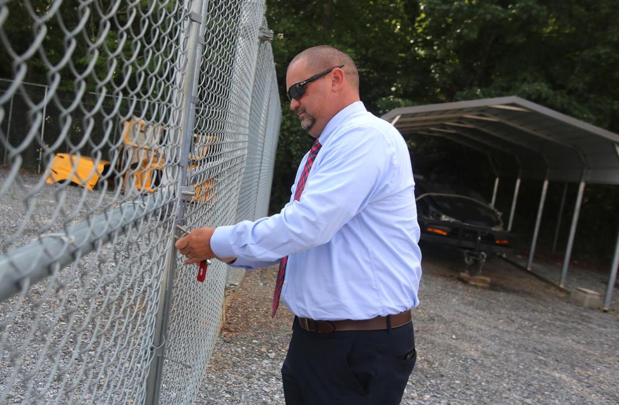 Cleveland County Schools Transportation Director David Pless opens the gate to the seized car lot on Thursday. Seized cars are auctioned off to benefit the Cleveland County Schools transportation department.