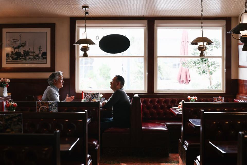 Two people sit at a diner booth