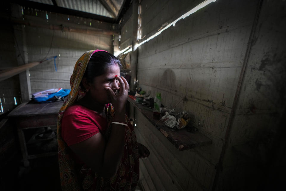 Busan Biswas, 51, wife of Hariprada Biswas, 66, who has not been able to prove his Indian citizenship, applies vermilion on her forehead at her house in Murkata village, north eastern Assam state, India, April 15, 2023. Nearly 2 million people, or over 5% of Assam's population, could be stripped of their citizenship unless they have documents dating back to 1971 that show their ancestors entered the country legally from neighboring Bangladesh. (AP Photo/Anupam Nath)