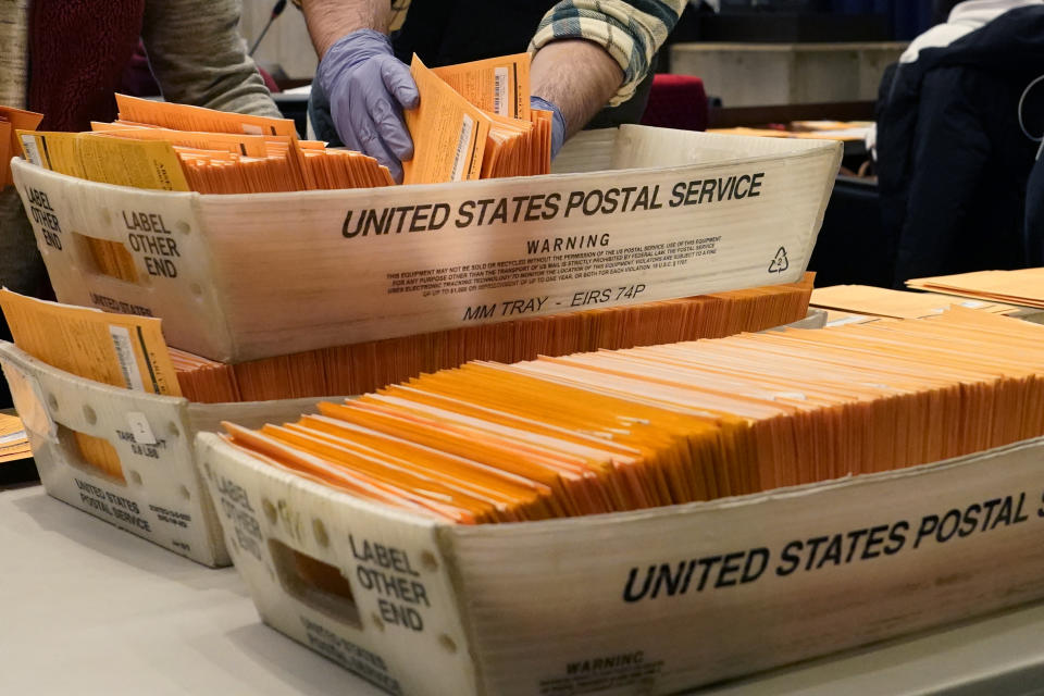 FILE - In this Nov. 2, 2020, file photo, Election officials sort absentee and early voting ballots for counting inside Boston City Hall in Boston. Democrats plan to move quickly on one of the first bills of the new Congress, which would set federal election standards. The For the People Act would require states to offer early voting, same-day registration and the option of absentee voting for all registered voters. (AP Photo/Elise Amendola, File)