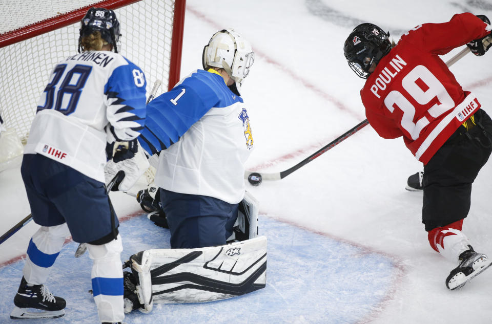 Finland goalie Anni Keisala, center, blocks a shot from Canada's Marie-Philip Poulin, right, as Finland's Ronja Savolaine looks on during the second period of an IIHF women's hockey championship game in Calgary, Alberta, Friday, Aug. 20, 2021. (Jeff McIntosh/The Canadian Press via AP)