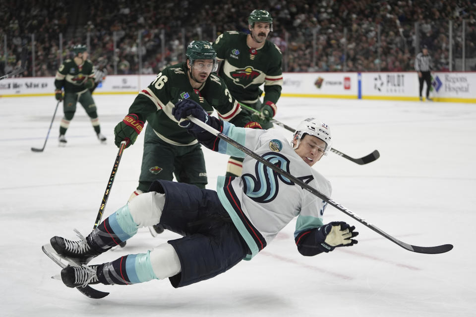 Minnesota Wild right wing Mats Zuccarello (36) trips Seattle Kraken center Yanni Gourde, front, during the second period of an NHL hockey game Thursday, April 18, 2024, in St. Paul, Minn. Zuccarello was penalized for tripping. (AP Photo/Abbie Parr)