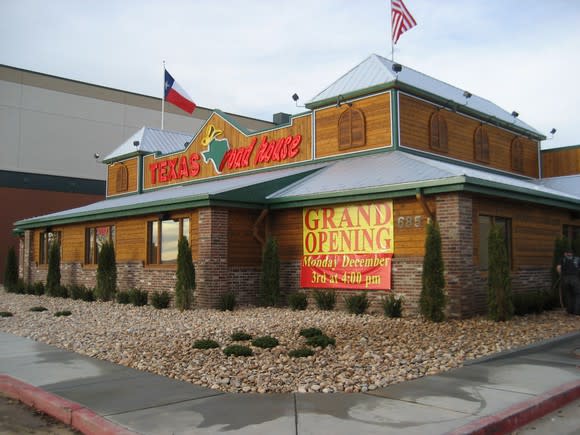 Texas Roadhouse restaurant location with grand opening sign and rock landscape.