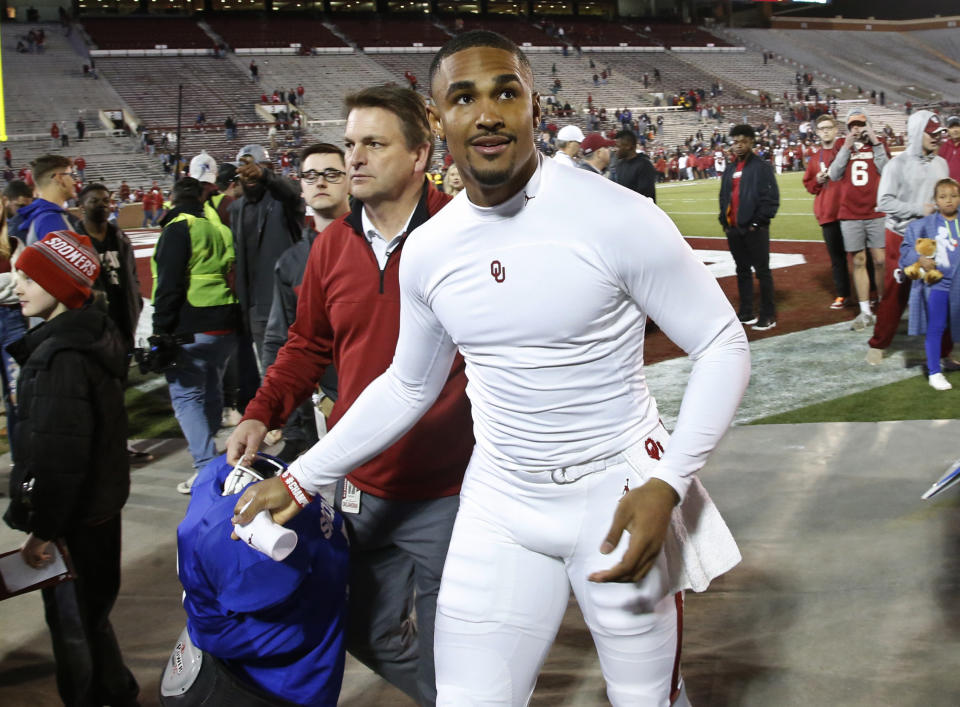 Oklahoma quarterback Jalen Hurts, right, prepares to throw a souvenir to a fan following an NCAA college football intra-squad spring game in Norman, Okla., Friday, April 12, 2019. (AP Photo/Sue Ogrocki)