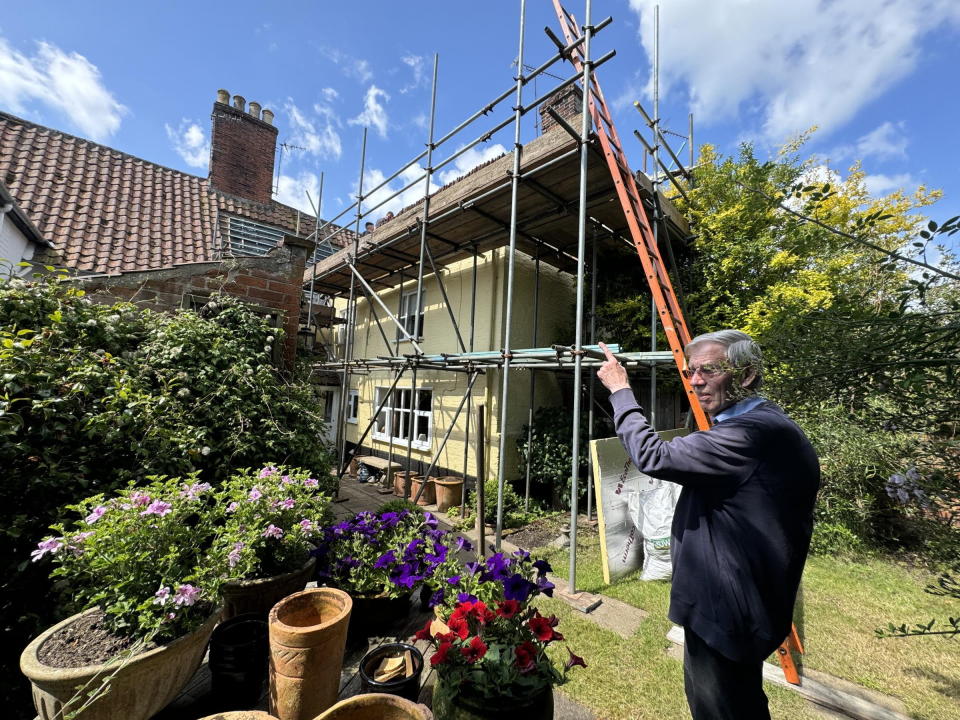Dr Andrew Jones pictured in his garden where scaffolding has been erected to repair his roof. (SWNS)