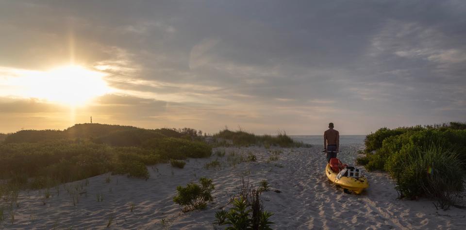 A fisherman pulls his kayak out to the beach just south of the Barnegat Inlet so her can head out for a morning of fishing. 